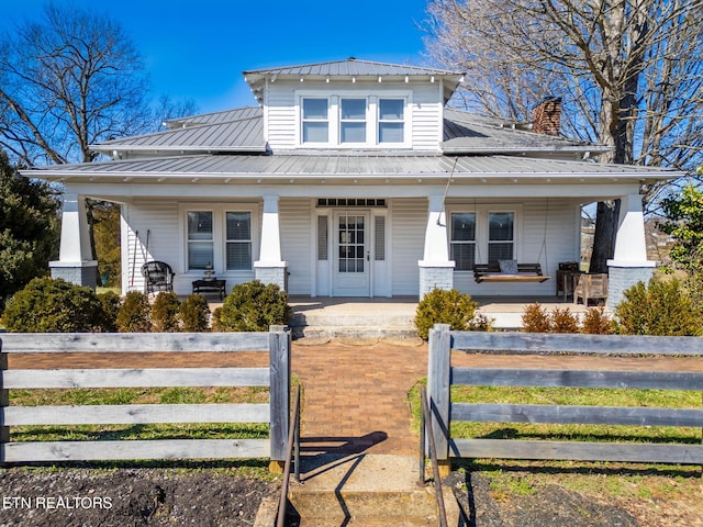 view of front of house with metal roof, a porch, and a fenced front yard