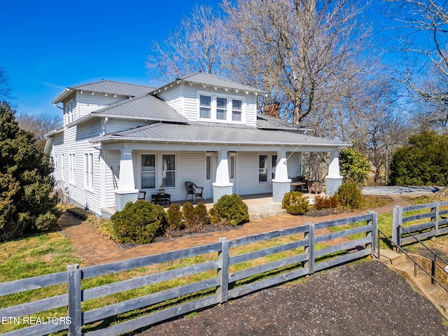 view of front of property featuring covered porch, a fenced front yard, and metal roof