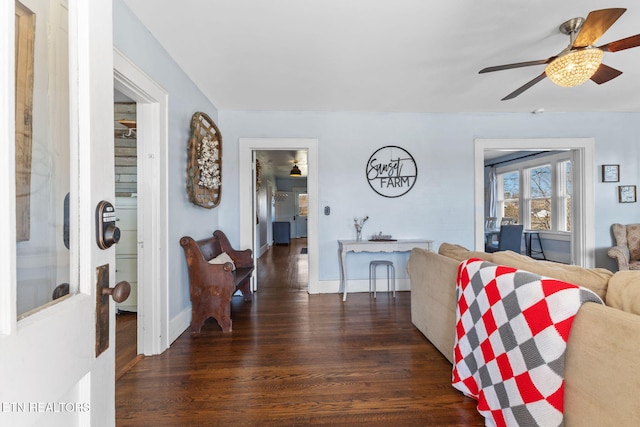 living room featuring a ceiling fan, baseboards, and wood finished floors