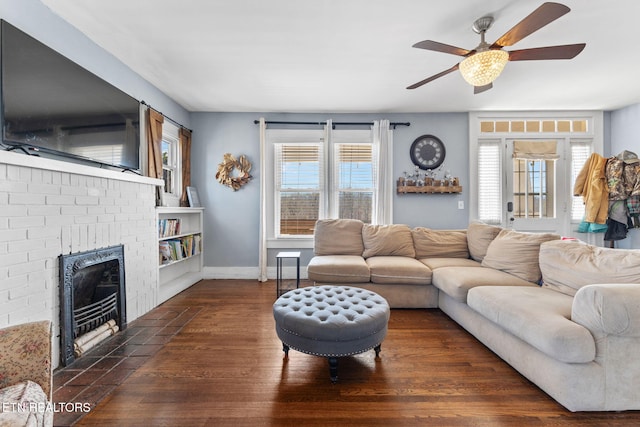 living area with a brick fireplace, plenty of natural light, baseboards, and wood finished floors