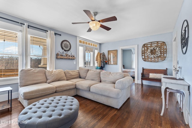 living area with dark wood-type flooring, a ceiling fan, and baseboards