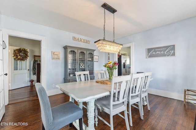 dining area with dark wood-style floors, baseboards, and an inviting chandelier