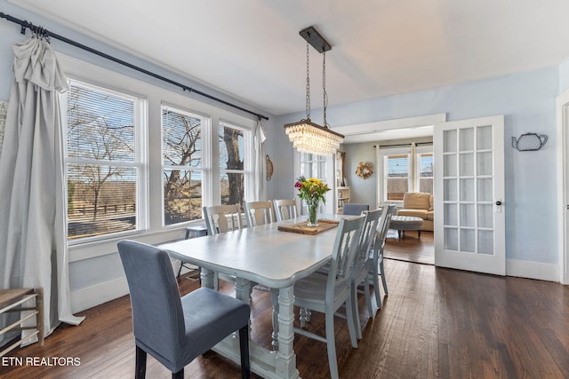 dining room with a notable chandelier, dark wood-style flooring, and baseboards