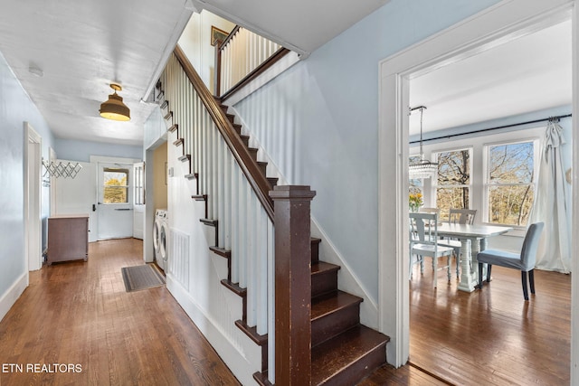 staircase with independent washer and dryer, baseboards, and hardwood / wood-style flooring