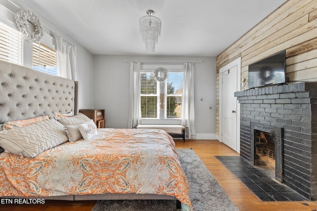 bedroom with a fireplace, wood finished floors, and baseboards