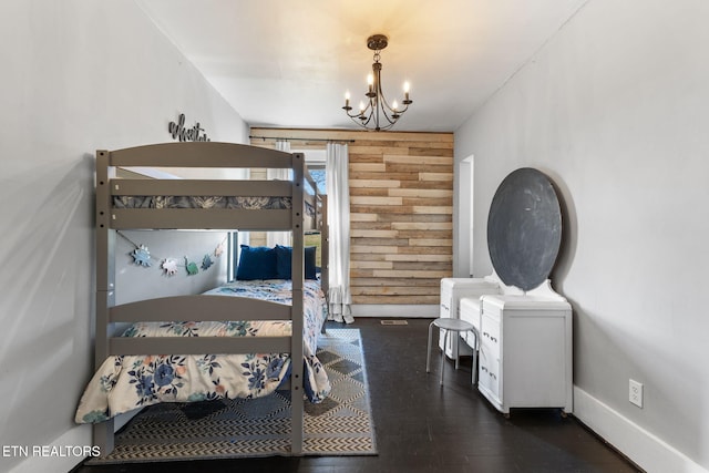 bedroom with a notable chandelier, wooden walls, baseboards, and wood finished floors