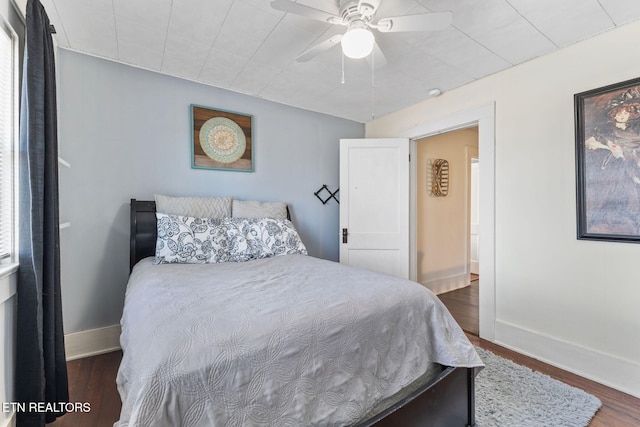 bedroom featuring wood finished floors, a ceiling fan, and baseboards