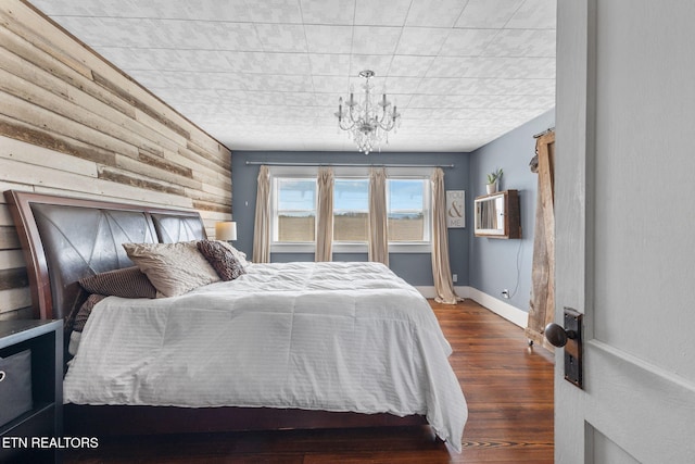 bedroom featuring baseboards, an inviting chandelier, and wood finished floors