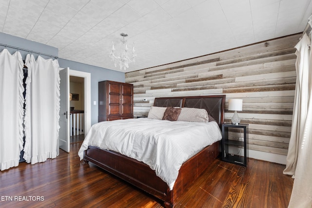 bedroom with wood walls, wood-type flooring, and a notable chandelier