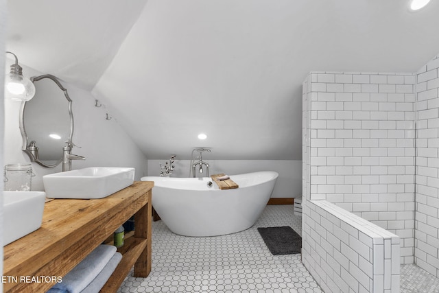 bathroom with a soaking tub, vaulted ceiling, a sink, and tiled shower