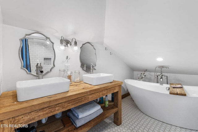 full bath with lofted ceiling, a soaking tub, a sink, and double vanity