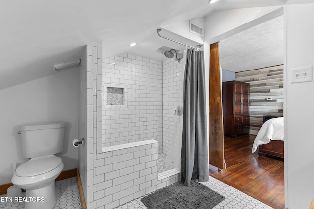 bathroom featuring lofted ceiling, tiled shower, toilet, and visible vents