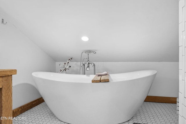 full bath with lofted ceiling, a freestanding tub, and baseboards