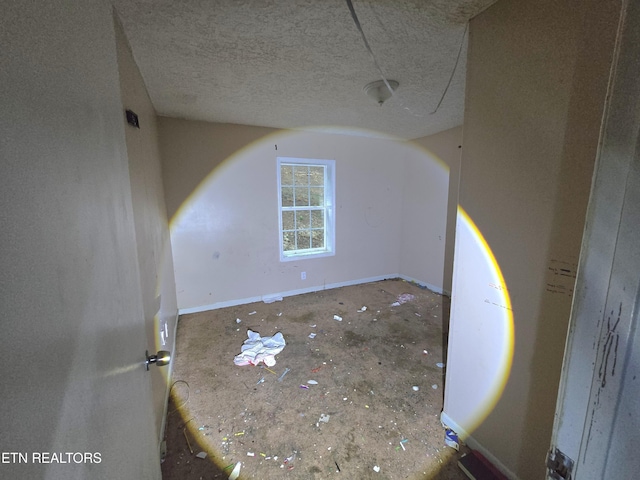 unfurnished room featuring a textured ceiling and baseboards