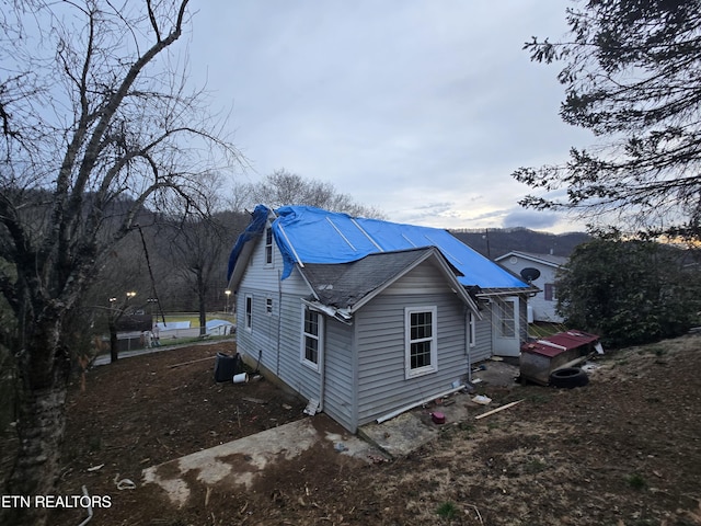 view of side of home featuring roof with shingles and central air condition unit