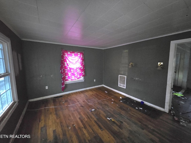 spare room with plenty of natural light, baseboards, visible vents, wood finished floors, and crown molding