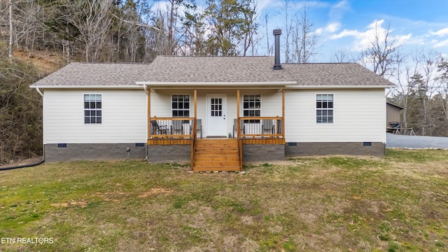 rear view of house featuring crawl space, covered porch, a shingled roof, and a lawn