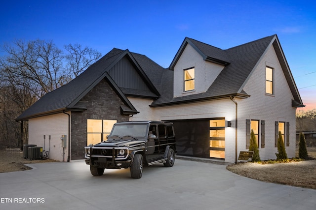 exterior space with brick siding, driveway, central AC, and roof with shingles