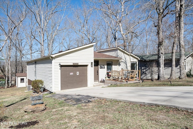 mid-century modern home featuring an attached garage, driveway, central AC, and an outbuilding