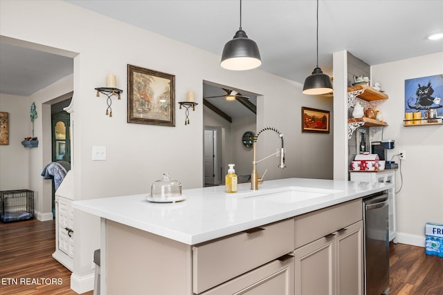 kitchen with dark wood-type flooring, decorative light fixtures, a sink, light countertops, and stainless steel dishwasher