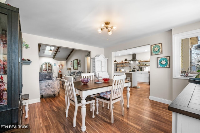 dining area featuring dark wood-type flooring, baseboards, and ceiling fan with notable chandelier