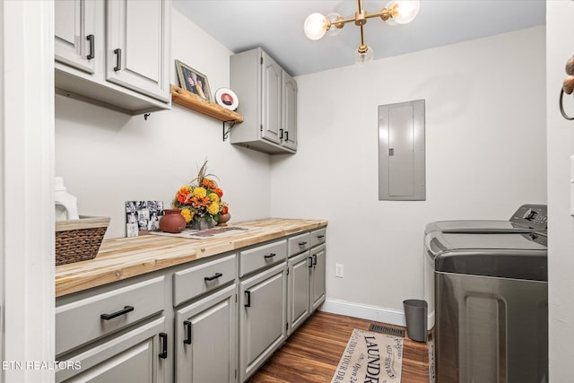 laundry room featuring dark wood-style flooring, washer and clothes dryer, cabinet space, electric panel, and baseboards