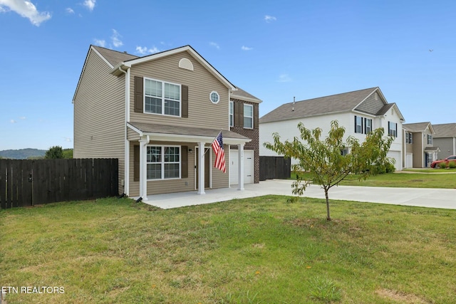 traditional home featuring a garage, fence, a front lawn, and concrete driveway