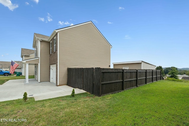 view of property exterior with concrete driveway, fence, and a lawn