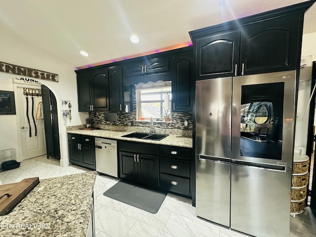 kitchen with arched walkways, decorative backsplash, marble finish floor, stainless steel appliances, and a sink