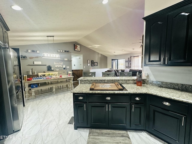 kitchen with black electric cooktop, a peninsula, vaulted ceiling, open floor plan, and freestanding refrigerator