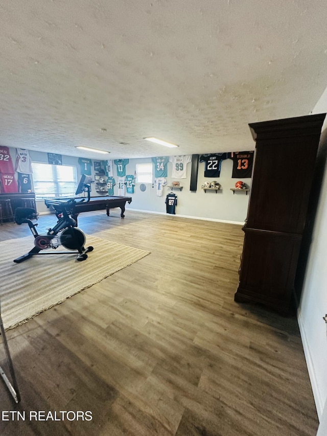 workout room with a textured ceiling, baseboards, and wood finished floors