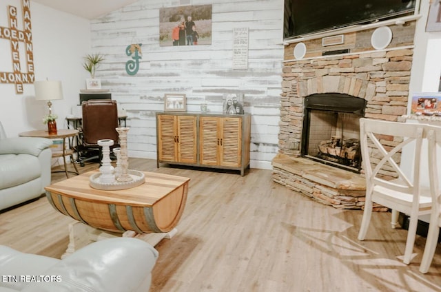 living area with vaulted ceiling, a fireplace, and wood finished floors