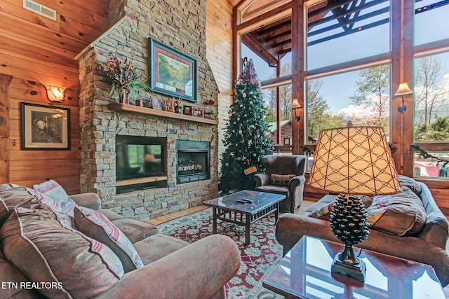 living area with wooden walls, a high ceiling, a fireplace, wood finished floors, and visible vents