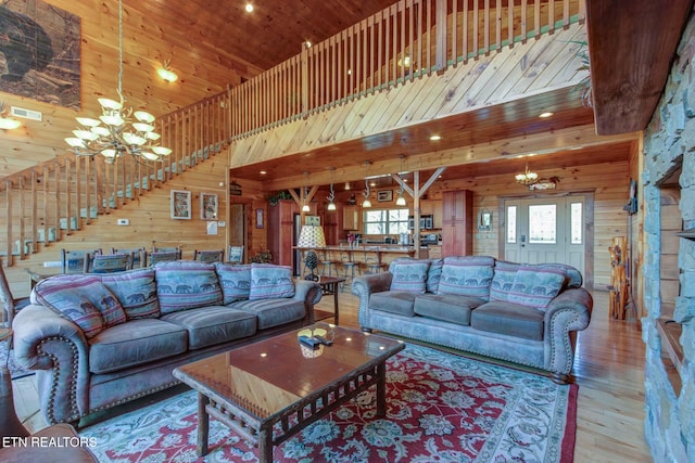 living room with wooden ceiling, a notable chandelier, wood walls, and visible vents