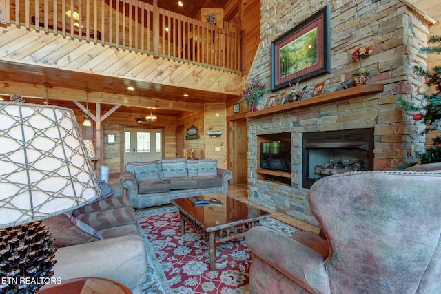 living area featuring a stone fireplace, wood walls, and a high ceiling