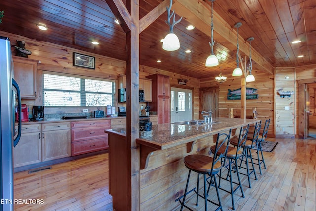 kitchen with wooden ceiling, wood walls, stainless steel fridge, and a sink