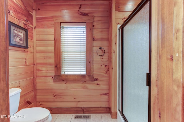 full bath with a shower stall, wooden walls, visible vents, and tile patterned flooring