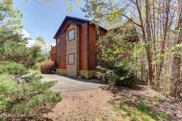 view of side of home with faux log siding and driveway