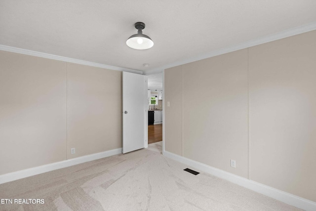 carpeted empty room featuring ornamental molding and baseboards