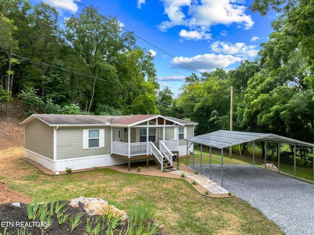 manufactured / mobile home with a detached carport, covered porch, driveway, and a front lawn