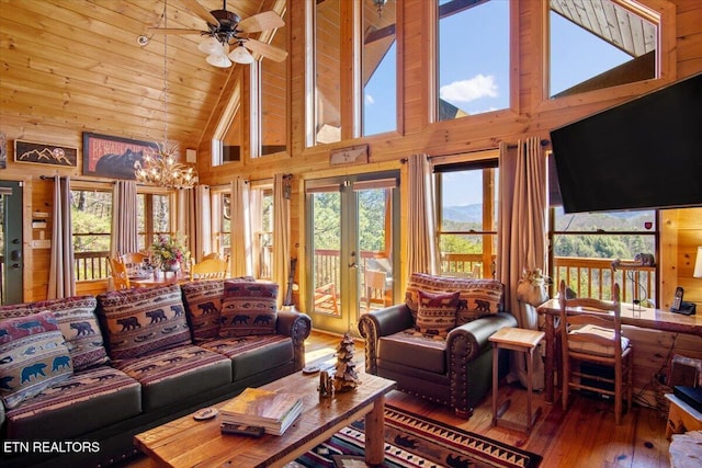 living area featuring wooden walls, high vaulted ceiling, wooden ceiling, hardwood / wood-style floors, and ceiling fan with notable chandelier