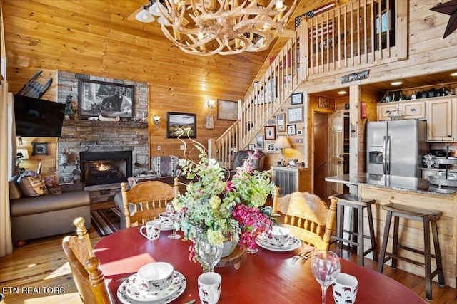 dining space with wood walls, stairs, high vaulted ceiling, and a fireplace