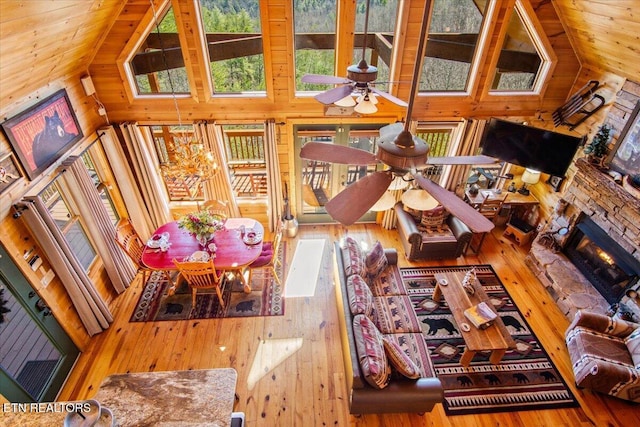 living room featuring high vaulted ceiling, a fireplace, hardwood / wood-style flooring, and a ceiling fan