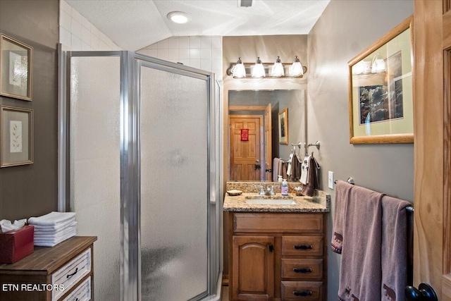 bathroom with vaulted ceiling, a stall shower, and vanity