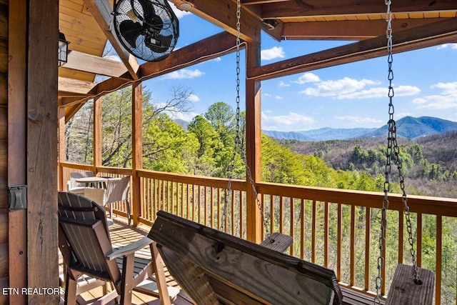 wooden deck featuring a wooded view and a mountain view