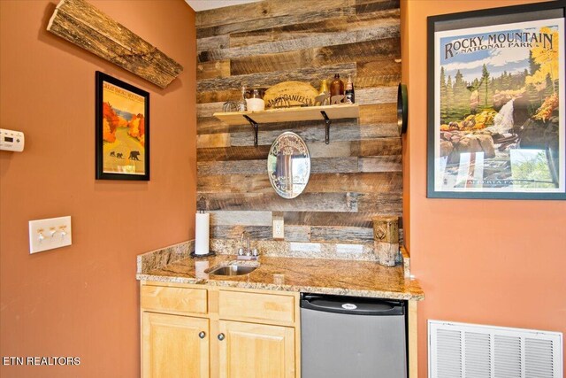 bar featuring dishwashing machine, wood walls, a sink, visible vents, and wet bar