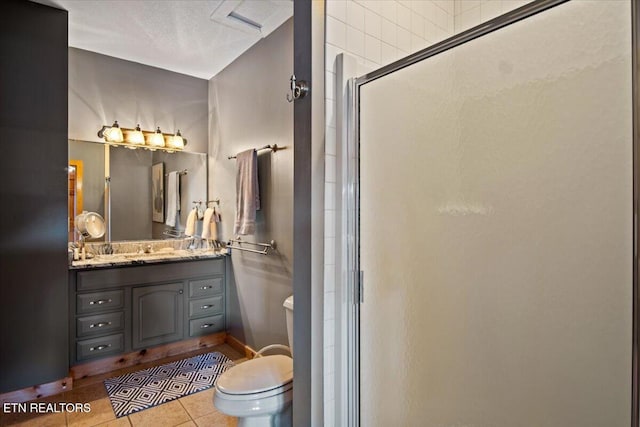 bathroom featuring toilet, a stall shower, tile patterned flooring, and vanity