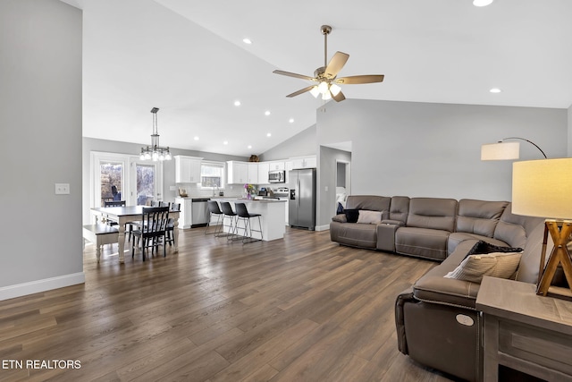 living room featuring dark wood-style floors, recessed lighting, high vaulted ceiling, baseboards, and ceiling fan with notable chandelier