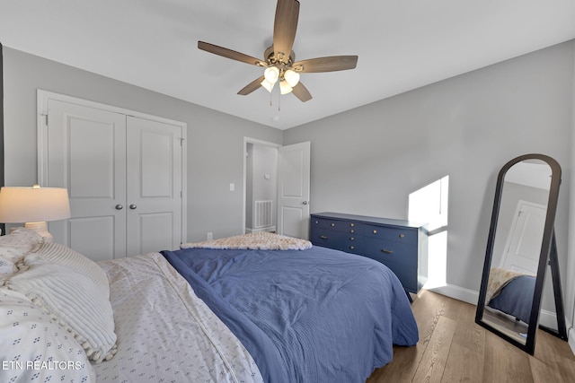 bedroom with a closet, ceiling fan, baseboards, and wood finished floors