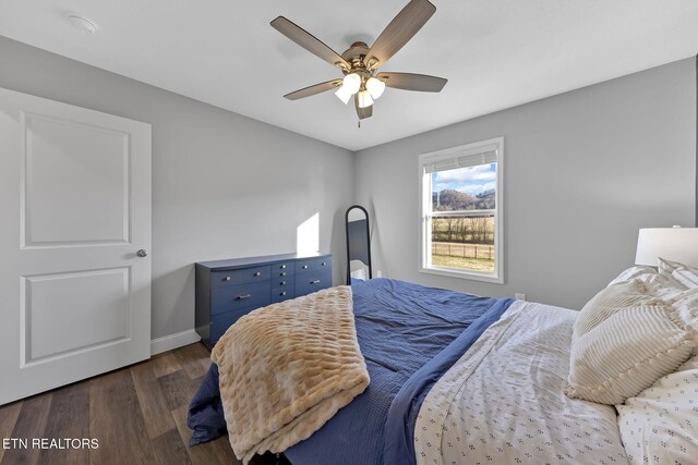 bedroom with a ceiling fan, dark wood-style flooring, and baseboards